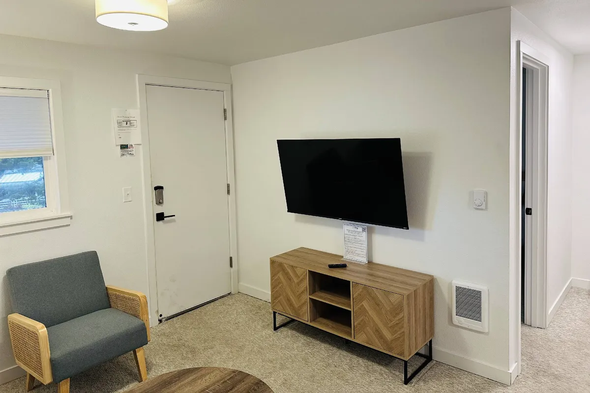 The image features a comfortable blue armchair, a wooden entertainment unit, and a television, creating a cozy spot for movie nights or casual gatherings. The setting encourages relaxation and social connection.
